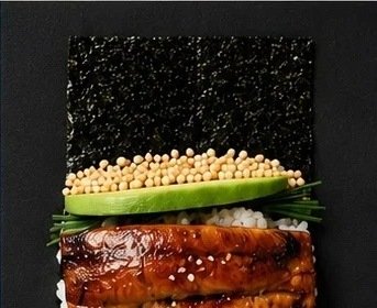 Hand roll topped with glazed eel, avocado and roe on a sheet of nori
